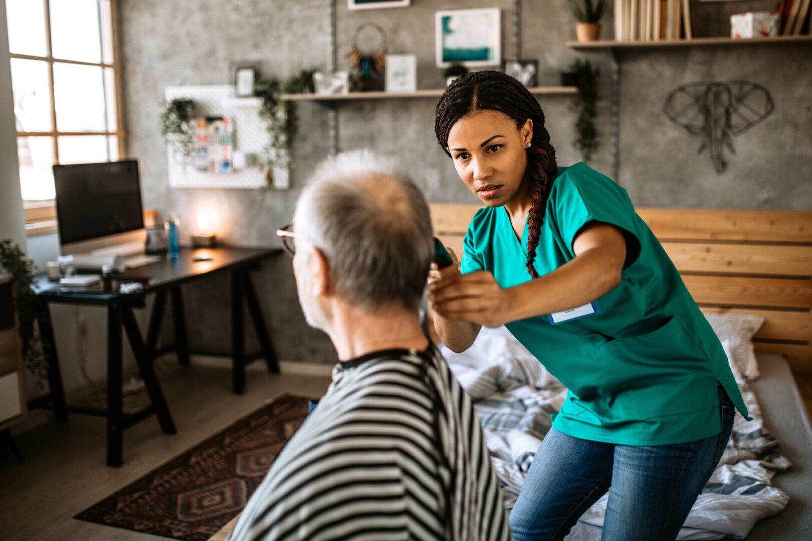 Mid adult black nurse giving a haircut to a senior man in nursing home