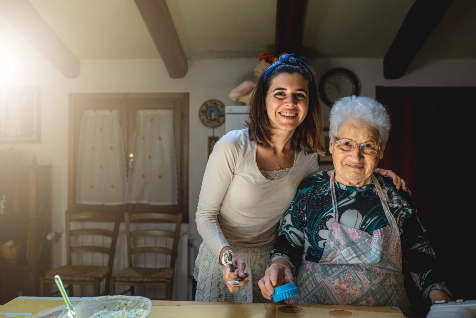A happy Caucasian grandmother teaching her granddaughter to make a dough and bake with the family recipe - happy family concept